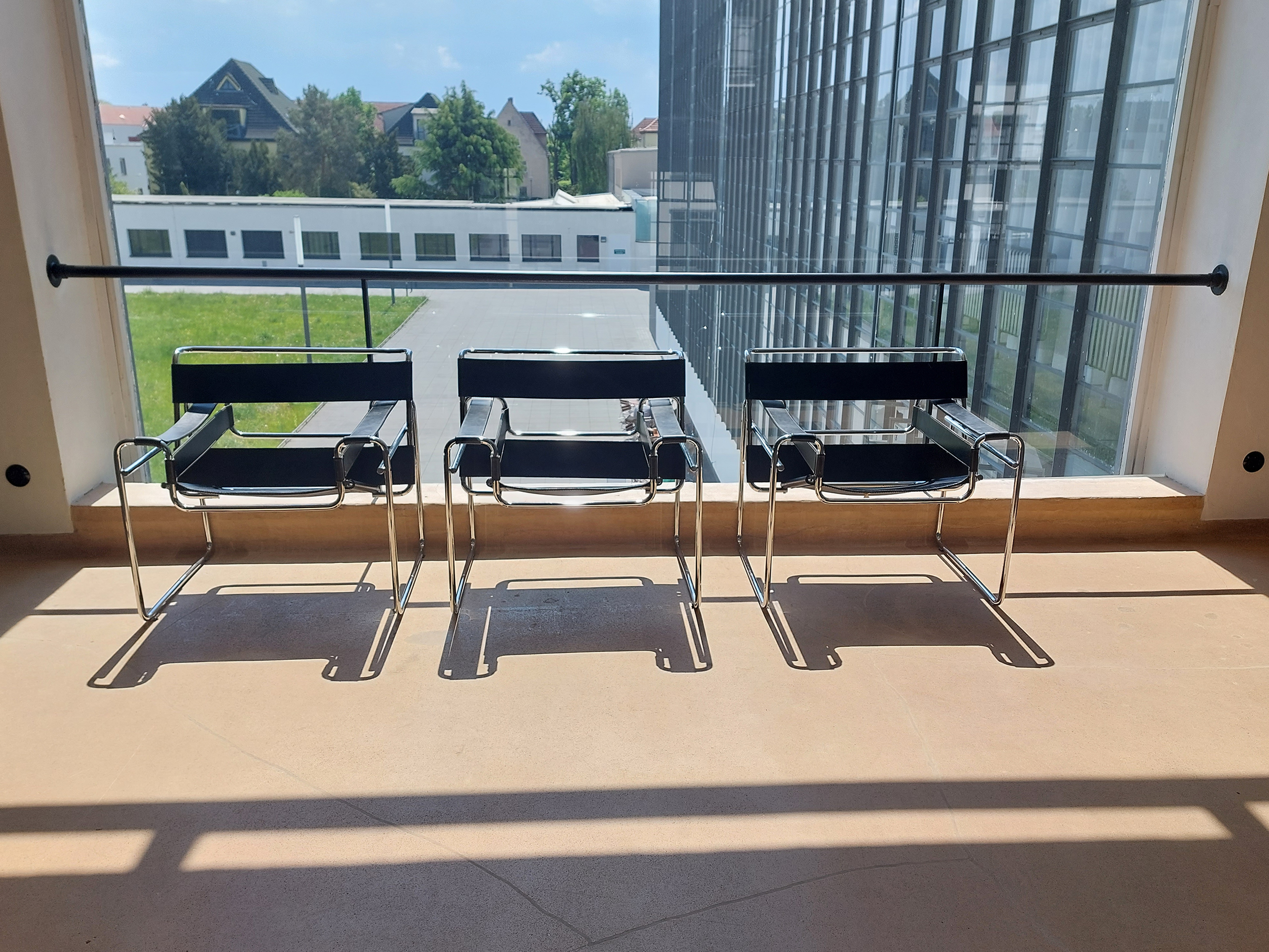 Drei Rohrsessel vor einem Glasfenster im Bauhaus-Gebäude in Dessau.